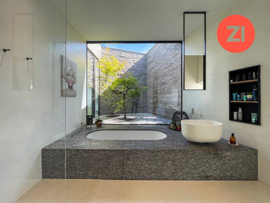 Luxuriöses Badezimmer mit freistehender Badewanne und Blick auf einen privaten Innenhof.