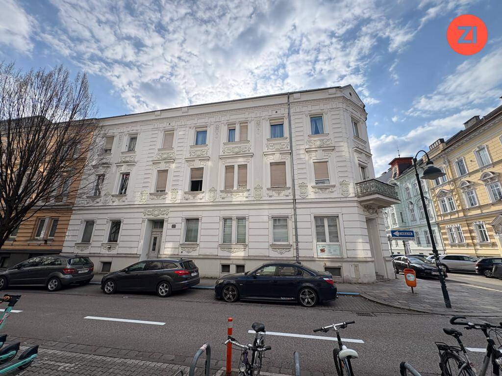 Lange Ansicht eines historischen Gebäudes mit weißer Fassade und vielen Fenstern entlang der Straße.