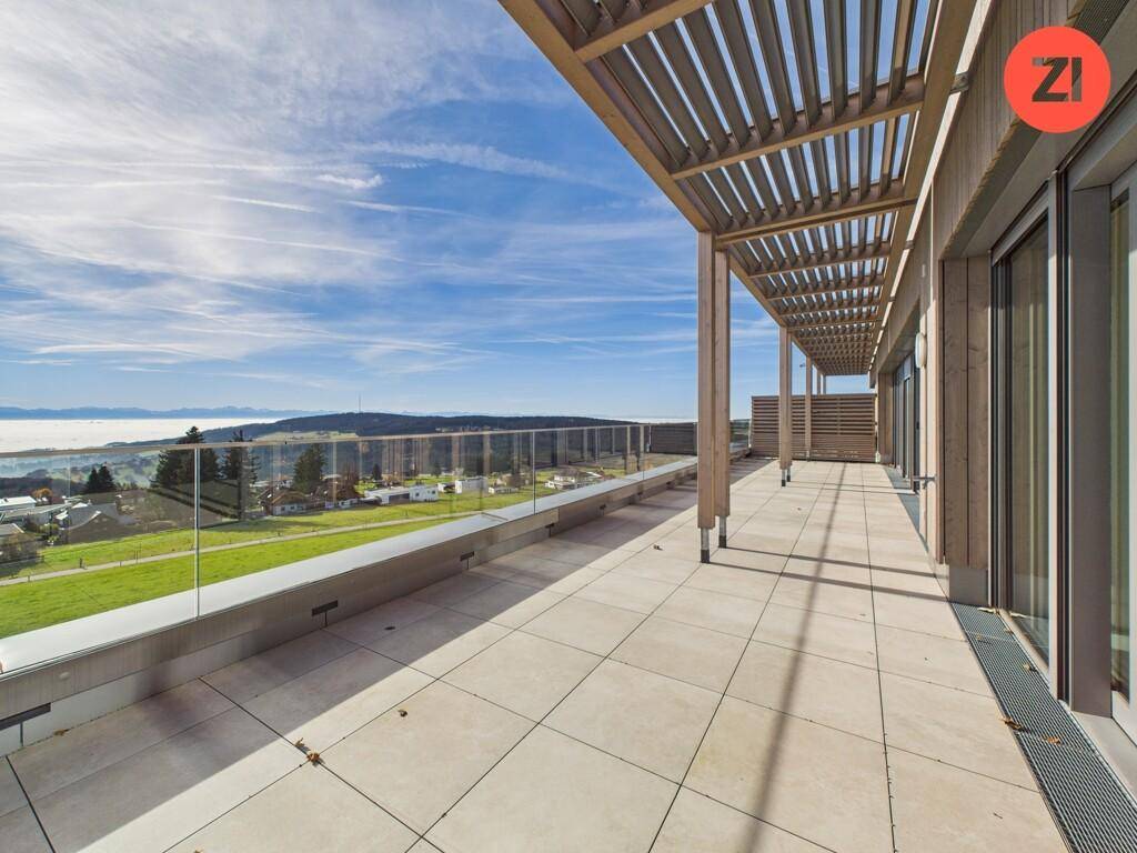Weitläufige Dachterrasse mit Pergola, Fliesenboden und Panoramablick über die Landschaft.