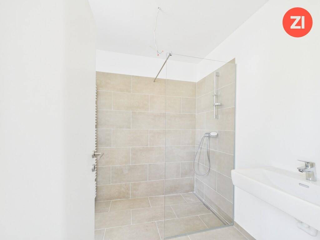 Modernes Badezimmer mit ebenerdiger Dusche, Fliesenboden und einem einzelnen Waschbecken.
