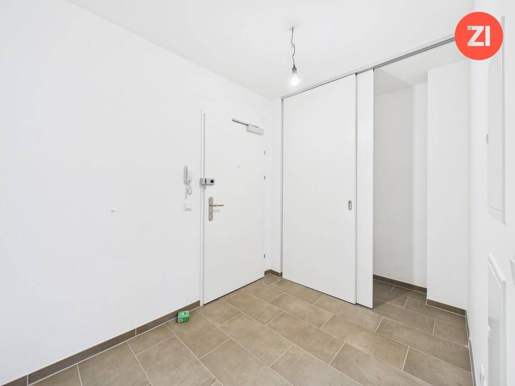 Eingangsbereich mit Fliesenboden, weiß gestrichenen Wänden und einer modernen Schiebetür.