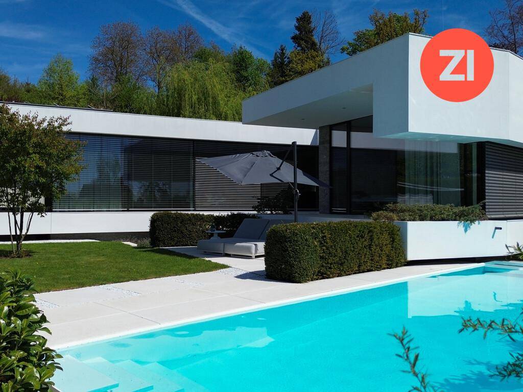 Exklusive moderne Villa mit großem Pool und gepflegtem Garten unter blauem Himmel.