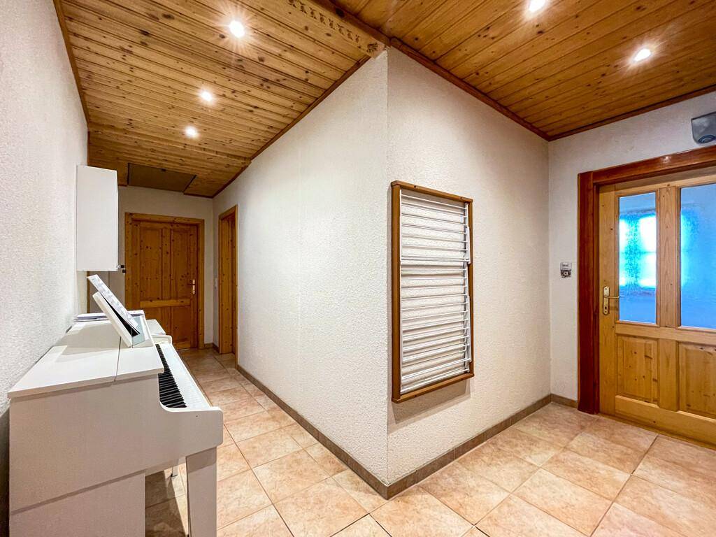 Geräumiger Flur mit Holzdecke, Fliesenboden und einem eleganten weißen Klavier.