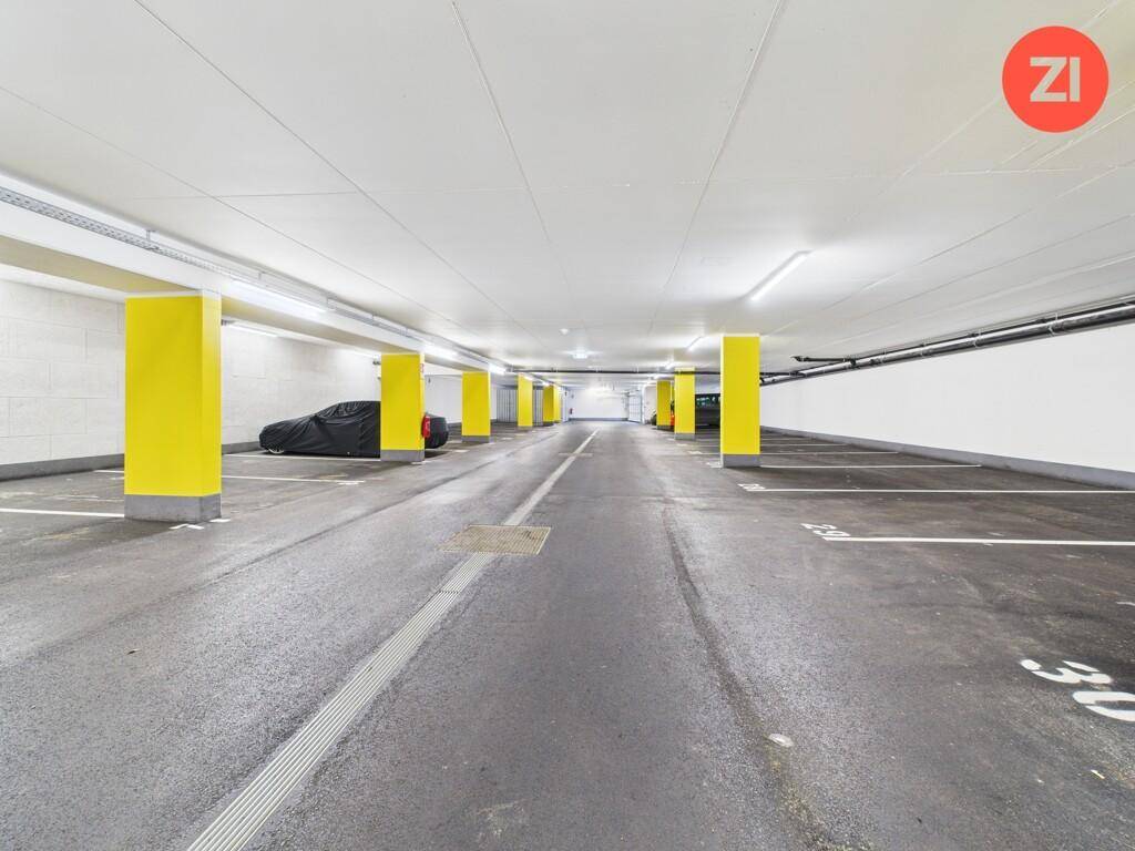 Geräumige Tiefgarage mit gelben Säulen und markierten Parkplätzen für Fahrzeuge.