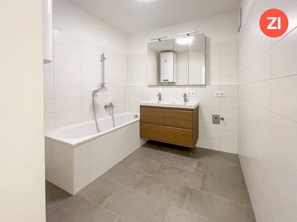 Modernes Badezimmer mit Badewanne, Doppelwaschbecken und großem Spiegelschrank.