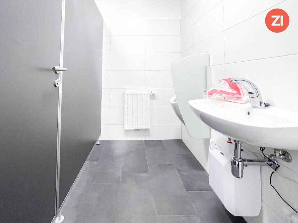 Modernes Herren-WC mit Urinal, Waschbecken und weißen Fliesen, in sehr gutem Zustand.