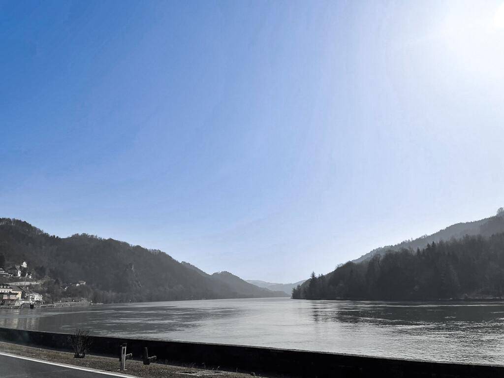 Panoramablick über einen breiten Fluss, der sich durch eine malerische Berglandschaft schlängelt.