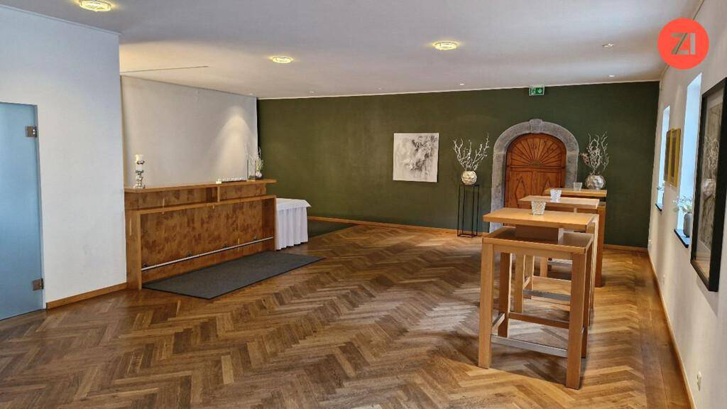 Veranstaltungsraum mit Holzboden im Fischgrätmuster, einer Bar und Stehtischen, ideal für Empfänge.