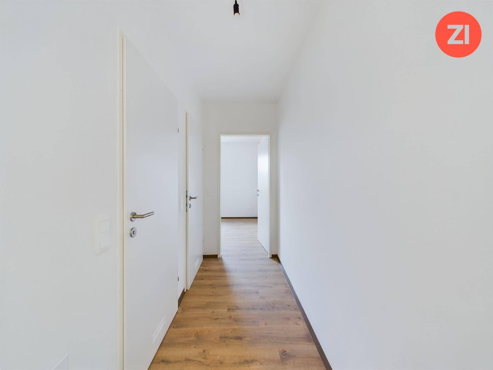 Langer, heller Flur mit Laminatboden und mehreren Türen, der verschiedene Räume verbindet.