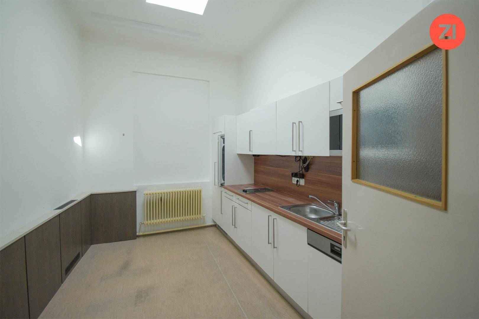 Kleine Küche mit weißen Schränken, Holz-Arbeitsplatte und Spülbecken, funktional und kompakt.