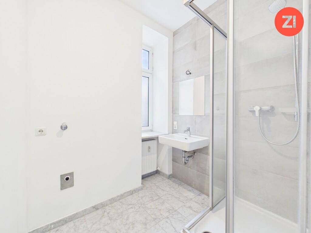 Helles Badezimmer mit moderner Duschkabine, Waschbecken und Fenster für natürliche Belüftung.