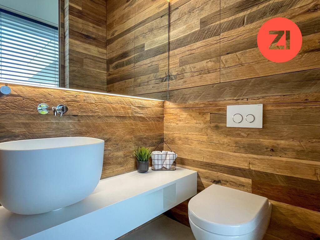 Elegantes Badezimmer mit Holzwänden, wandhängendem WC und modernem Waschbecken.