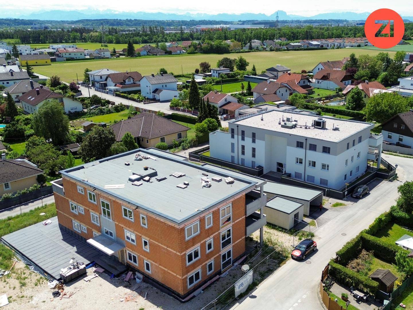 Luftaufnahme einer Neubauanlage mit zwei Mehrfamilienhäusern in ländlicher Umgebung mit viel Grün.