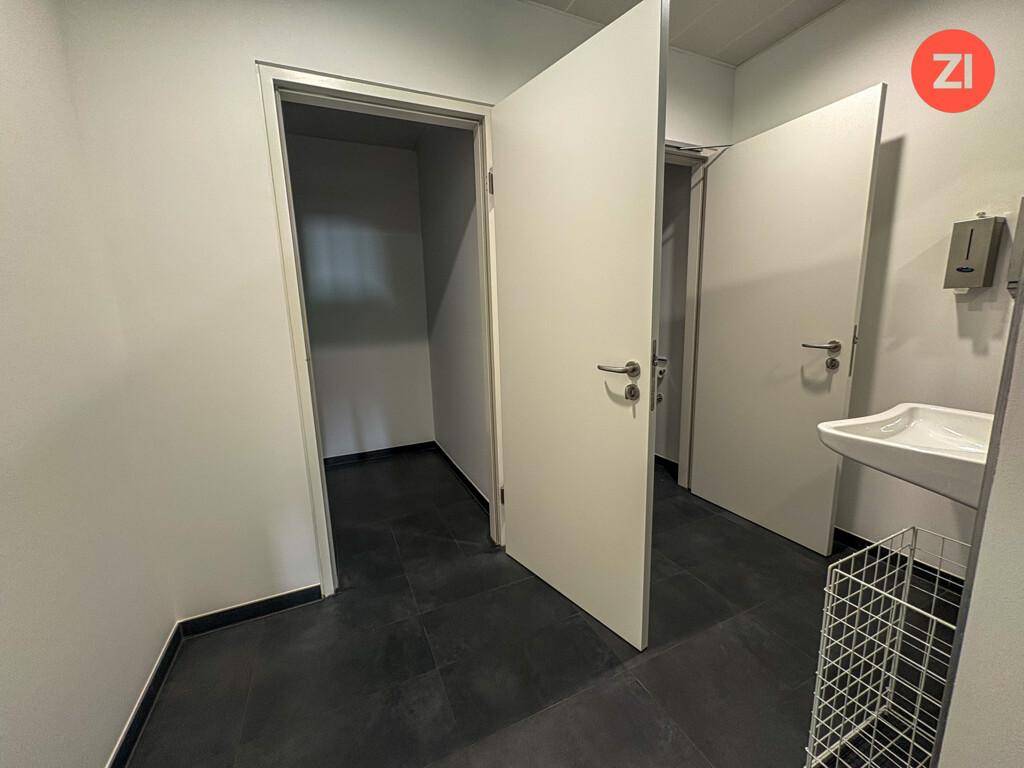 Eingangsbereich zu den Toiletten mit Waschbecken und dunklem Fliesenboden.