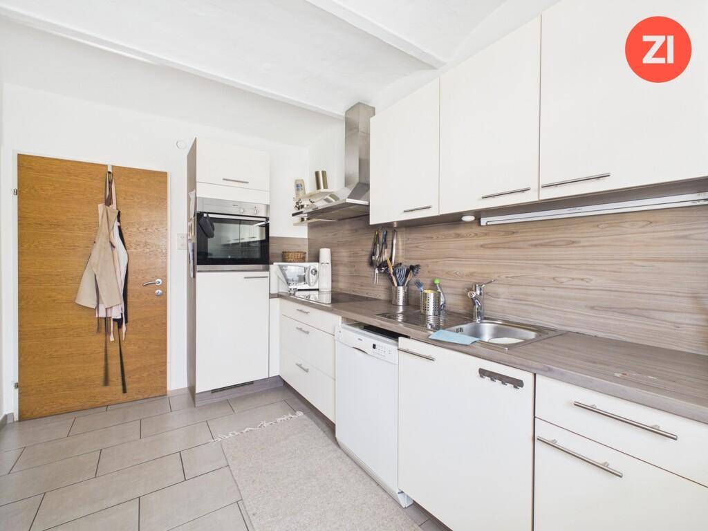 Moderne Einbauküche mit weißen Fronten, Holzdekor und praktischer Ausstattung.