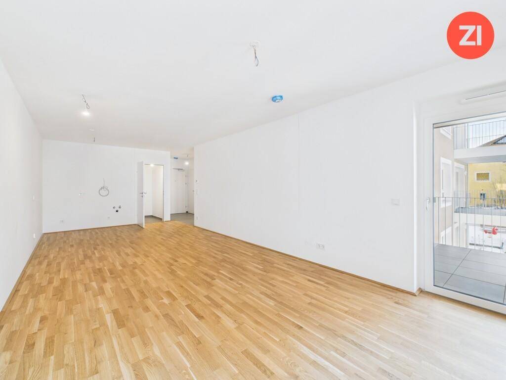 Geräumiger, heller Wohnbereich mit Holzparkett und direktem Zugang zum Außenbereich.
