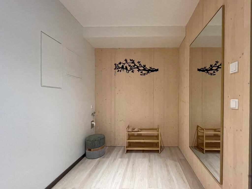 Heller Eingangsbereich mit großem Spiegel, Schuhregal und Holzwand.