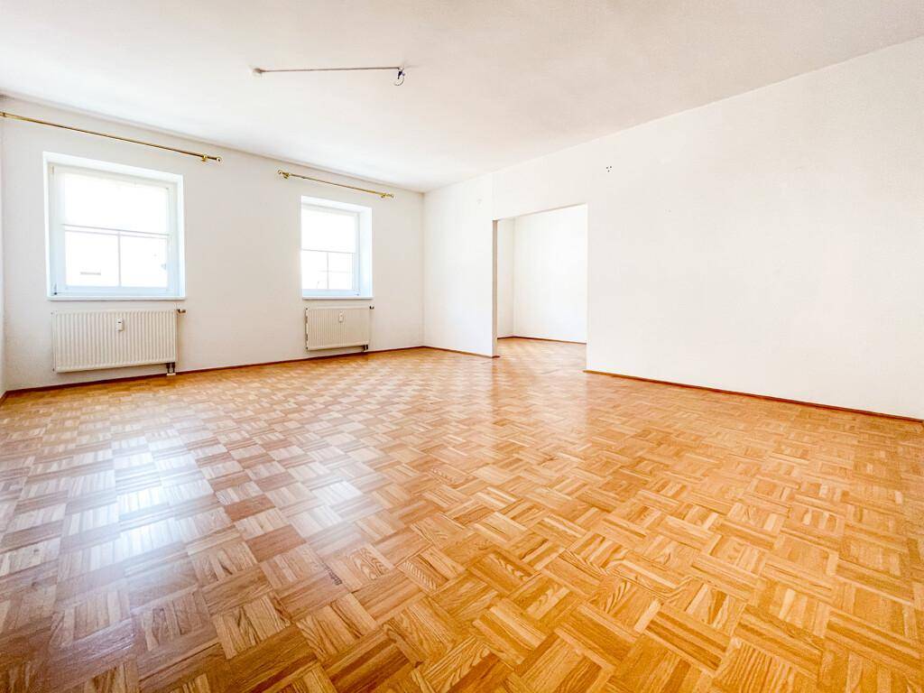 Geräumiges, helles Wohnzimmer mit Parkettboden und großen Fenstern, ideal für individuelle Einrichtung.