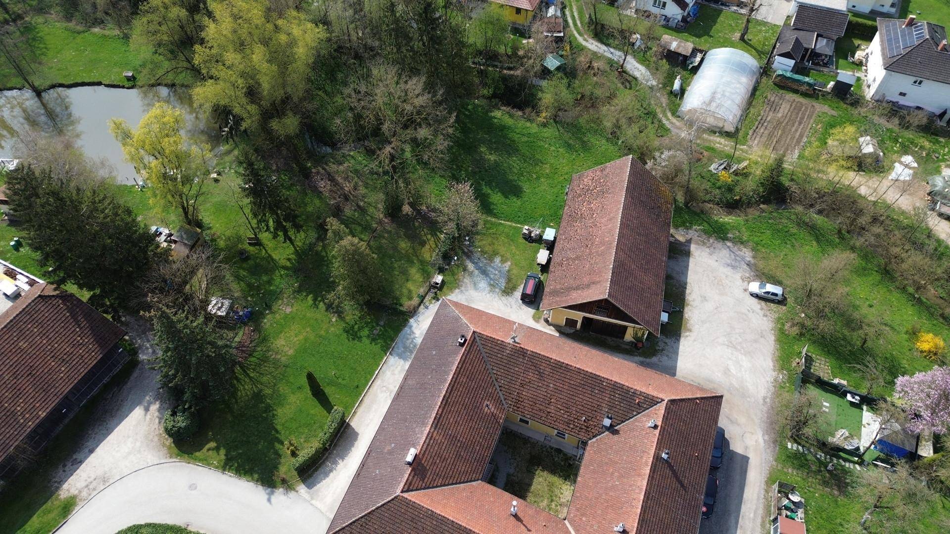Luftaufnahme des Anwesens mit mehreren Gebäuden, einem Teich und weitläufigen Grünflächen in ländlicher Umgebung.