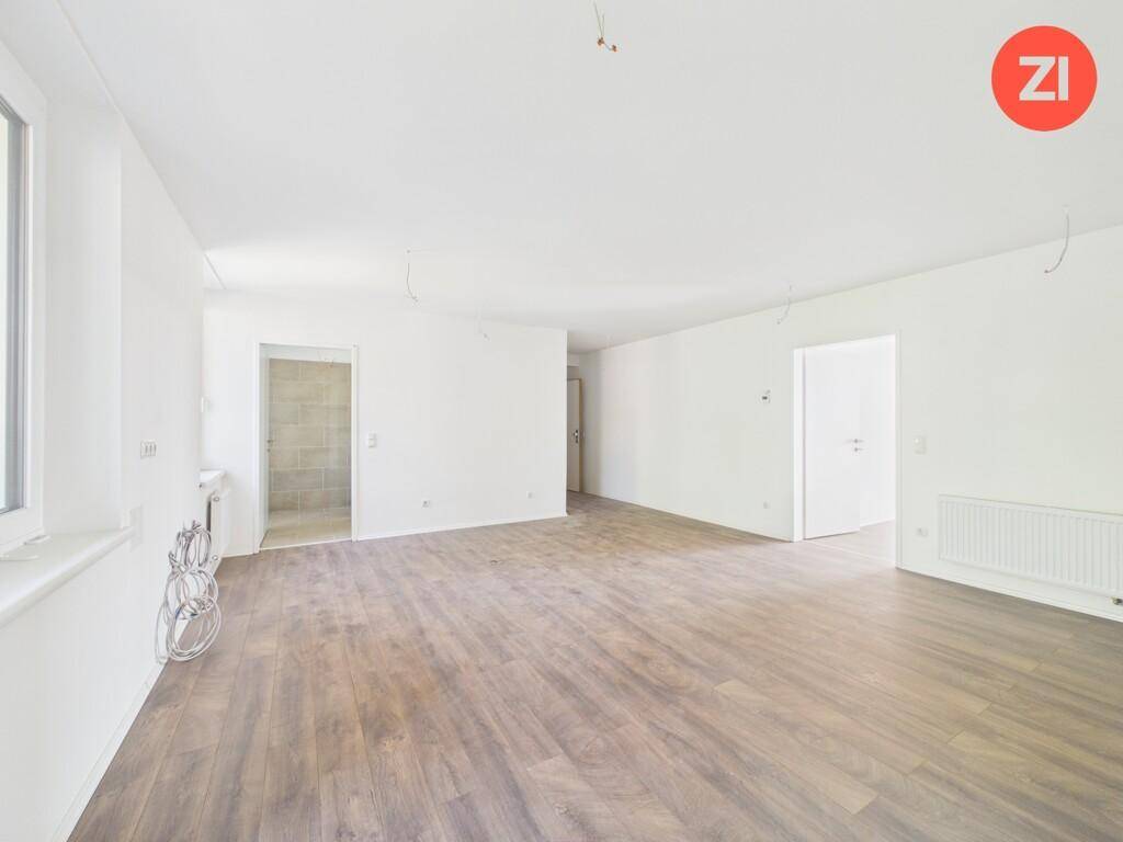 Großer, heller Wohnbereich mit Laminatboden und Zugang zu verschiedenen weiteren Räumen.