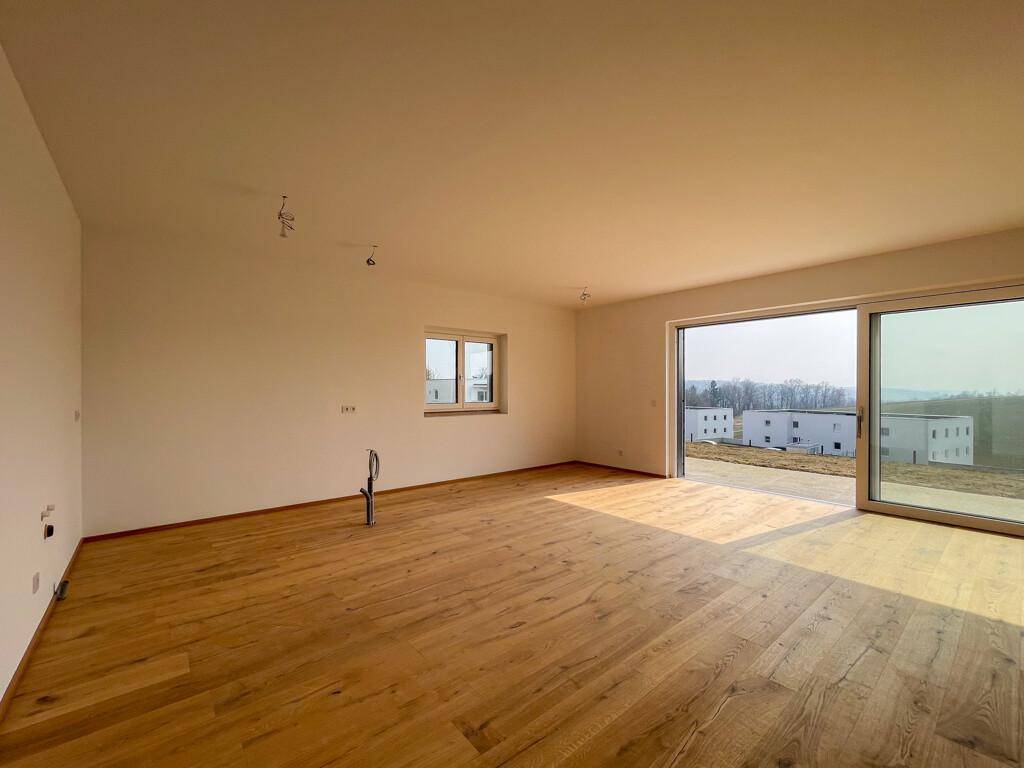 Helles Wohnzimmer mit Holzboden, großen Fenstern und Schiebetür mit Weitblick.
