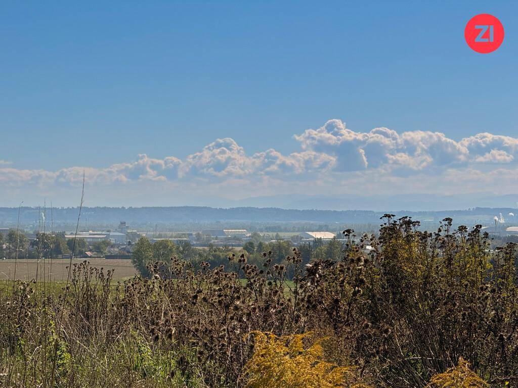 Panoramablick über eine weite Landschaft mit Industrieanlagen und Wolken am Horizont.