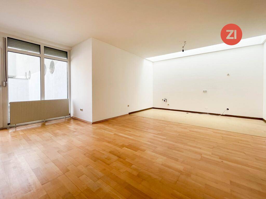 Heller Raum mit Holzparkettboden und großem Fenster mit Rollladen, bietet vielseitige Nutzungsmöglichkeiten.