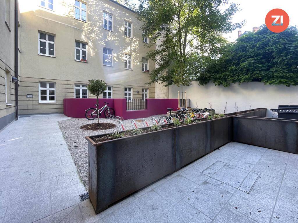 Gepflegter Innenhof mit Fahrradabstellplätzen, Pflanzbeeten und einem Grillbereich.