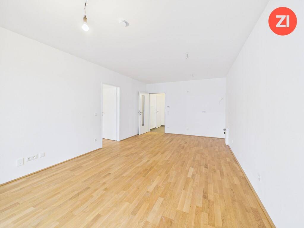 Geräumiger, leerer Raum mit hellem Parkettboden und mehreren Türen zu angrenzenden Zimmern.