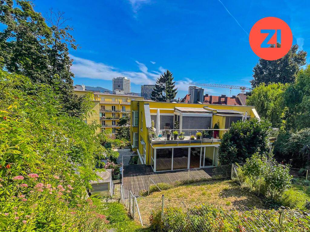 Gelbes Mehrfamilienhaus mit Balkonen, Terrasse und Garten in grüner Umgebung.