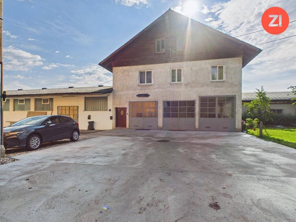 Vorderansicht eines Gebäudes mit mehreren Garagentoren und einem großen gepflasterten Vorplatz.