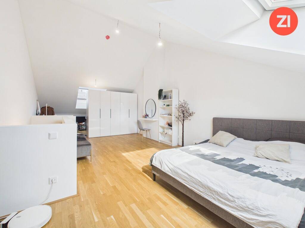 Großes Schlafzimmer im Dachgeschoss mit Einbauschränken, Schminktisch und Holzboden.