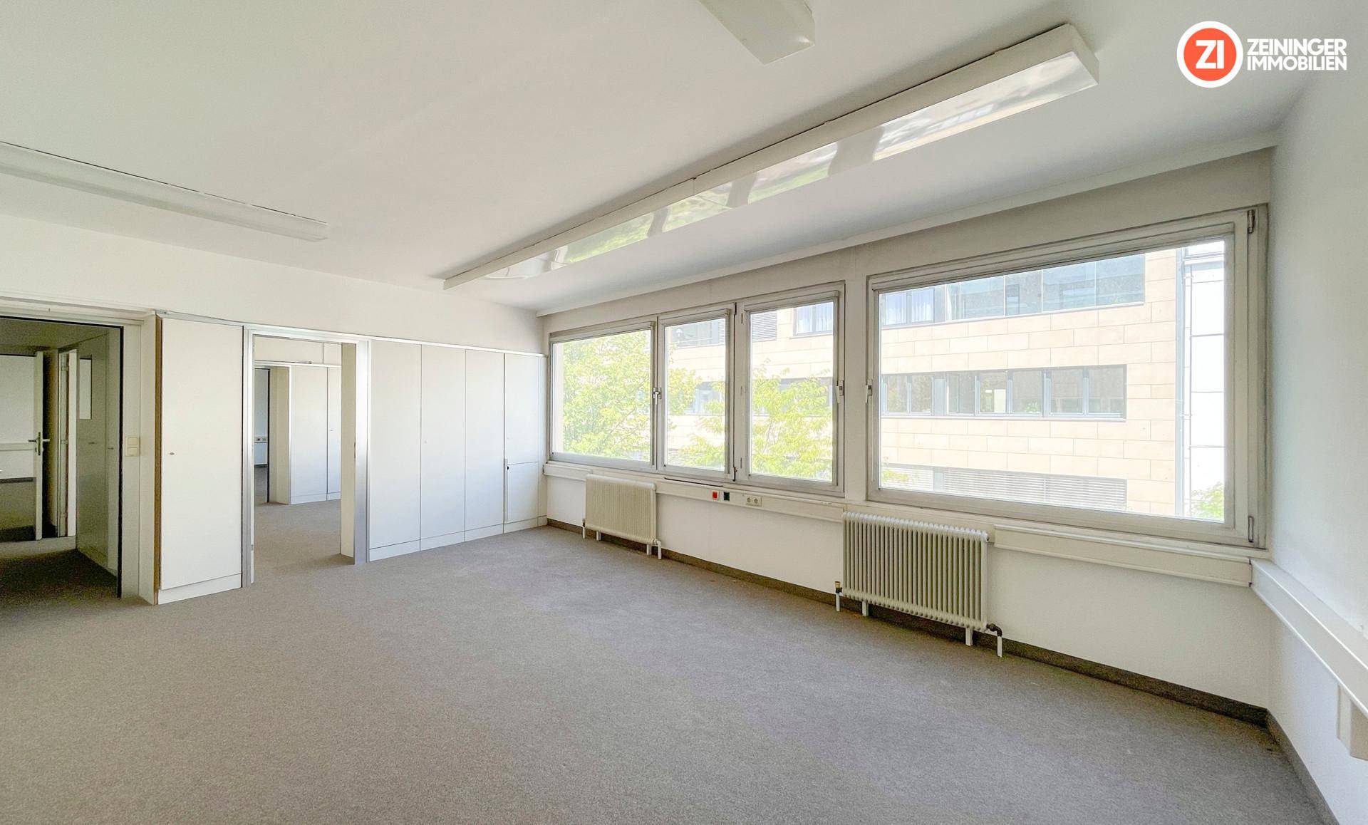 Großer, heller Büroraum mit mehreren Fenstern und effizienter Deckenbeleuchtung, ideal für Arbeitsbereiche.