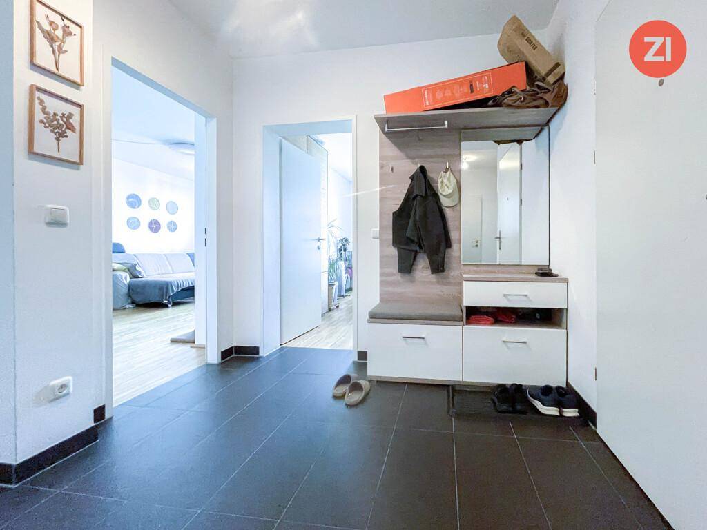 Flur mit dunklen Fliesen, Garderobe und Blick in den Wohnbereich.