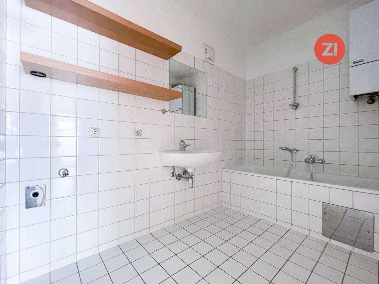 Badezimmer mit weißen Fliesen, Badewanne, Waschbecken und praktischen Holzregalen an der Wand.