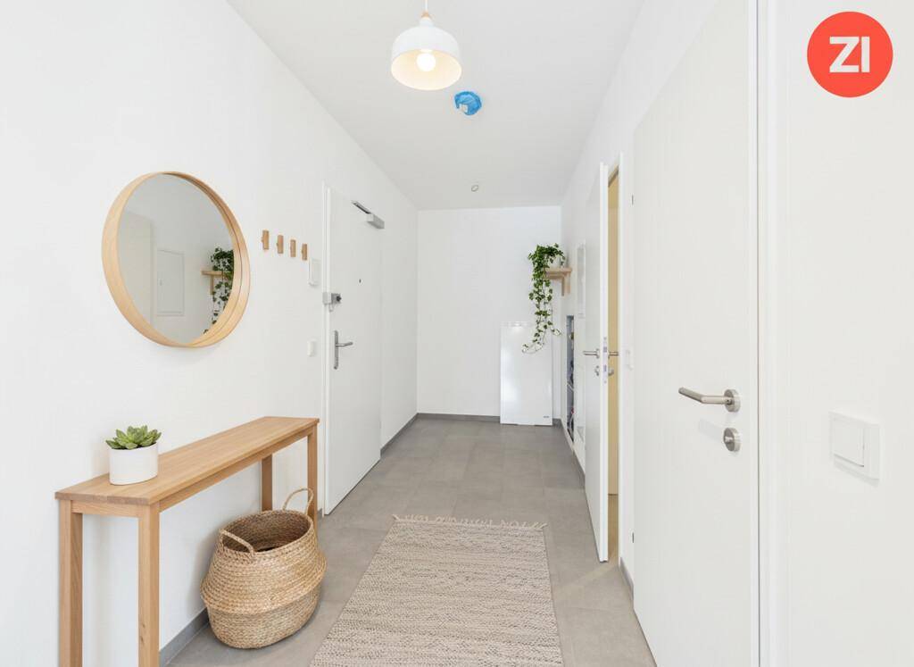Heller Flur mit modernem Design, Fliesenboden und runden Spiegel.