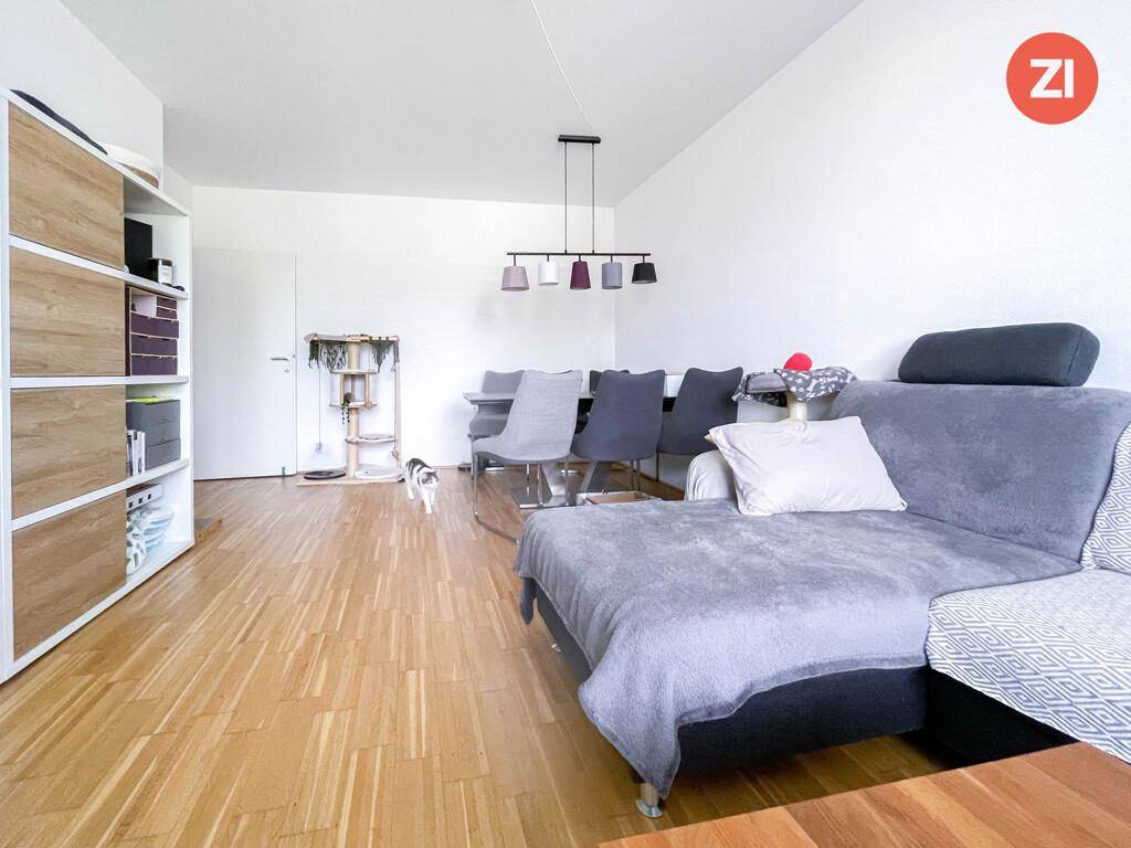 Offener Wohn- und Essbereich mit Holzboden, Sofa und Esstisch.