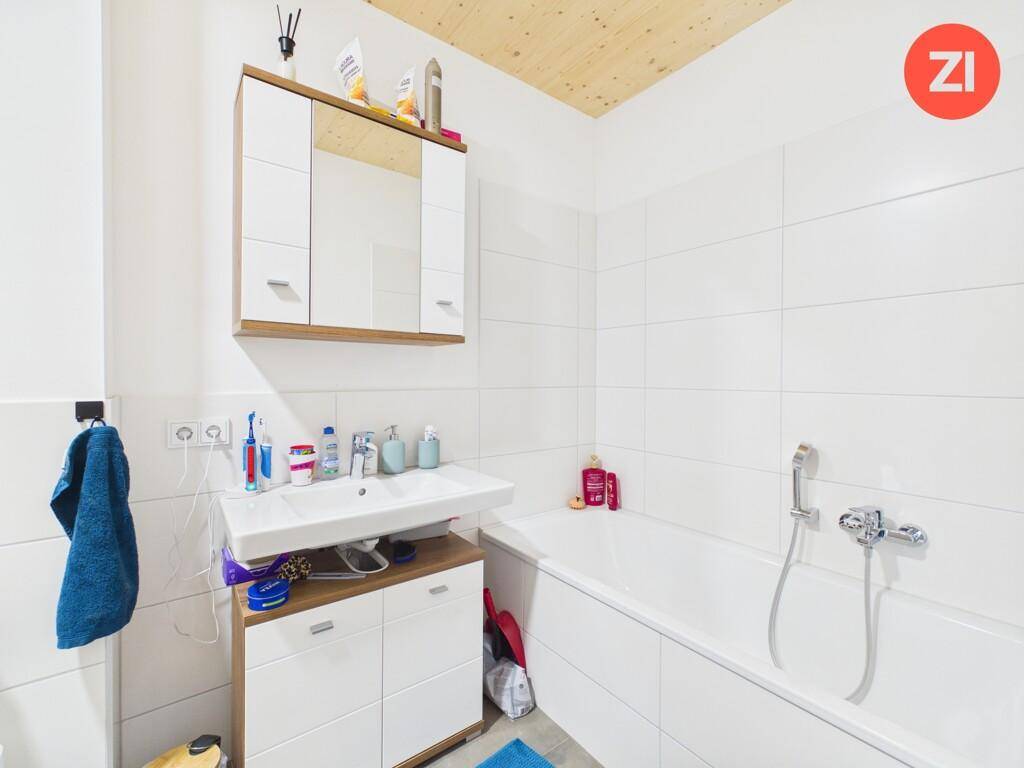 Modernes Badezimmer mit Badewanne, Waschbecken, Spiegelschrank und weißen Fliesen.