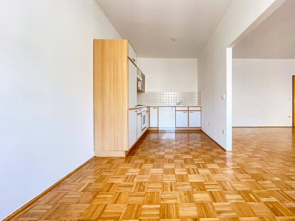Kleine Küchenzeile mit hellen Schränken und Parkettboden, offen zum Wohnbereich.