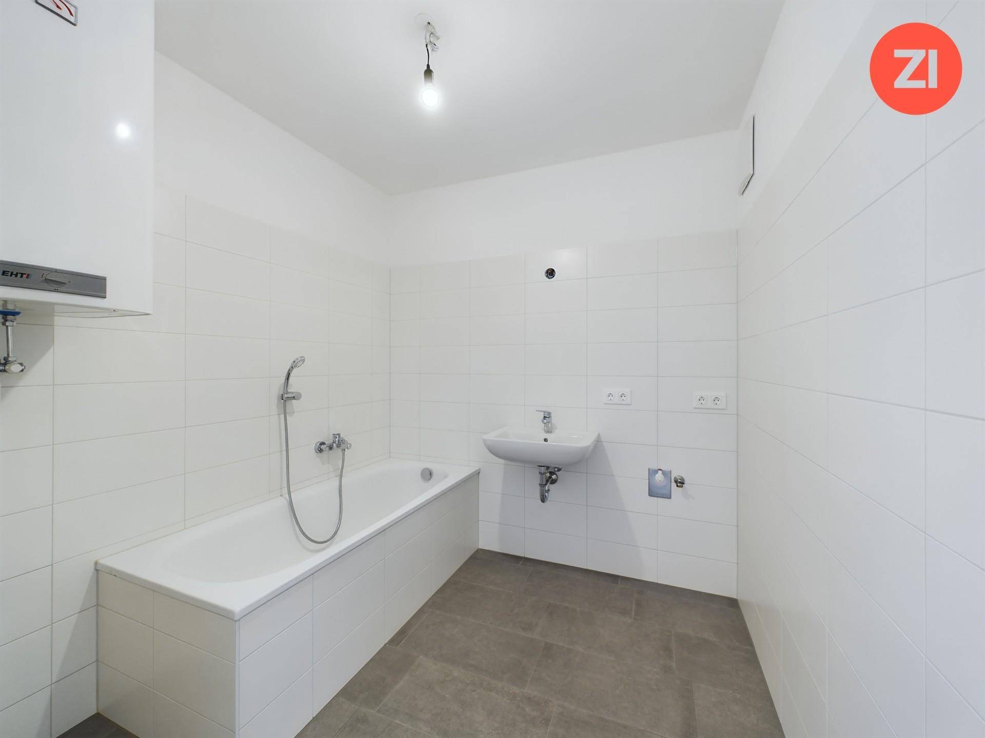 Modernes Badezimmer mit Badewanne, Waschbecken und weißen Fliesen an den Wänden und am Boden.