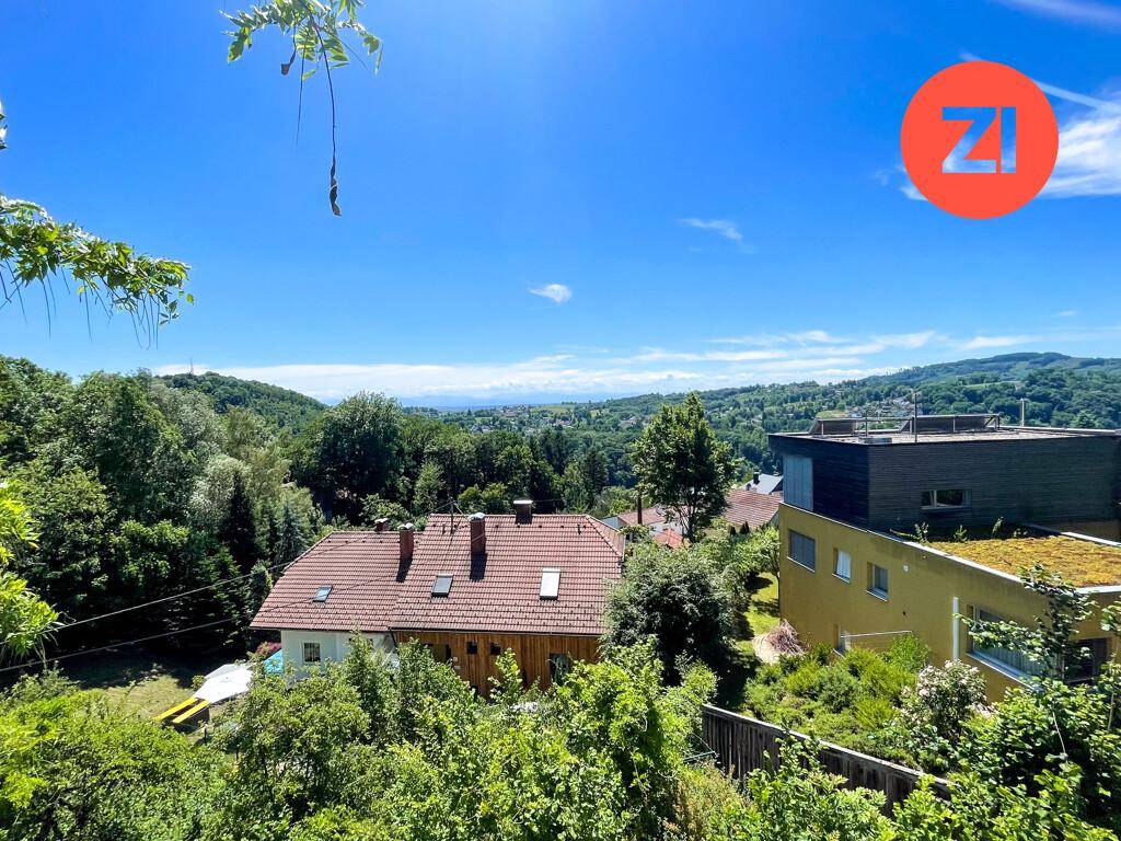 Haus mit rotem Ziegeldach, umgeben von dichter Vegetation, mit weitem Blick in die Landschaft.