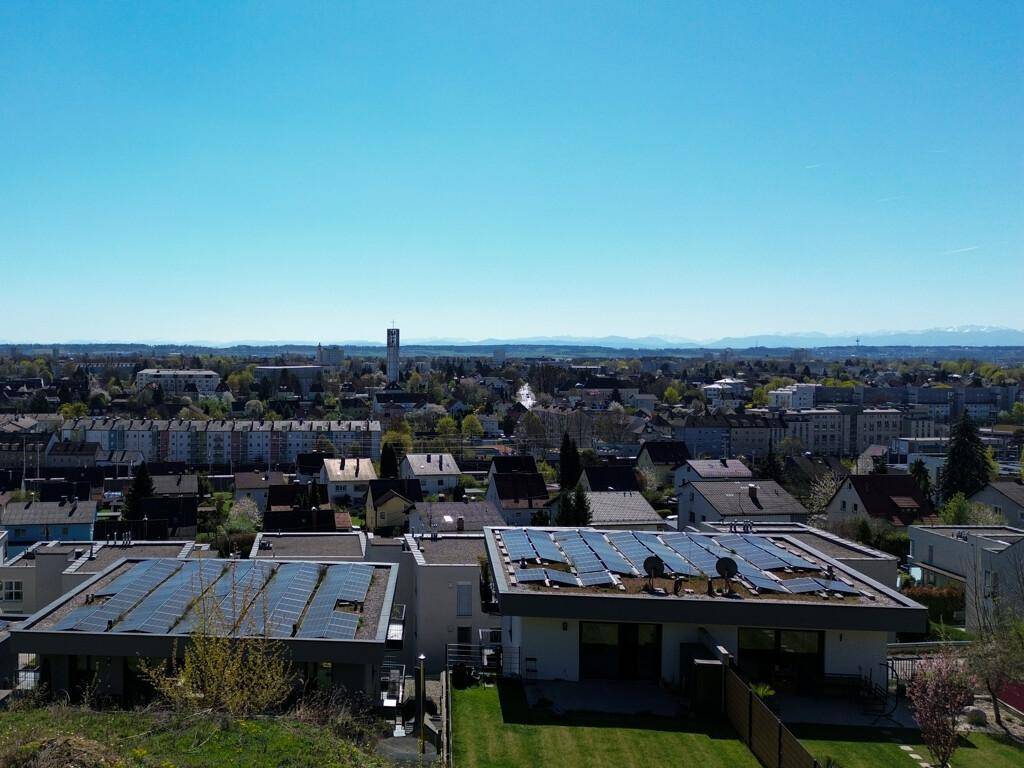 Luftaufnahme einer Wohnsiedlung mit vielen Häusern, Solaranlagen und einem weiten Horizont.