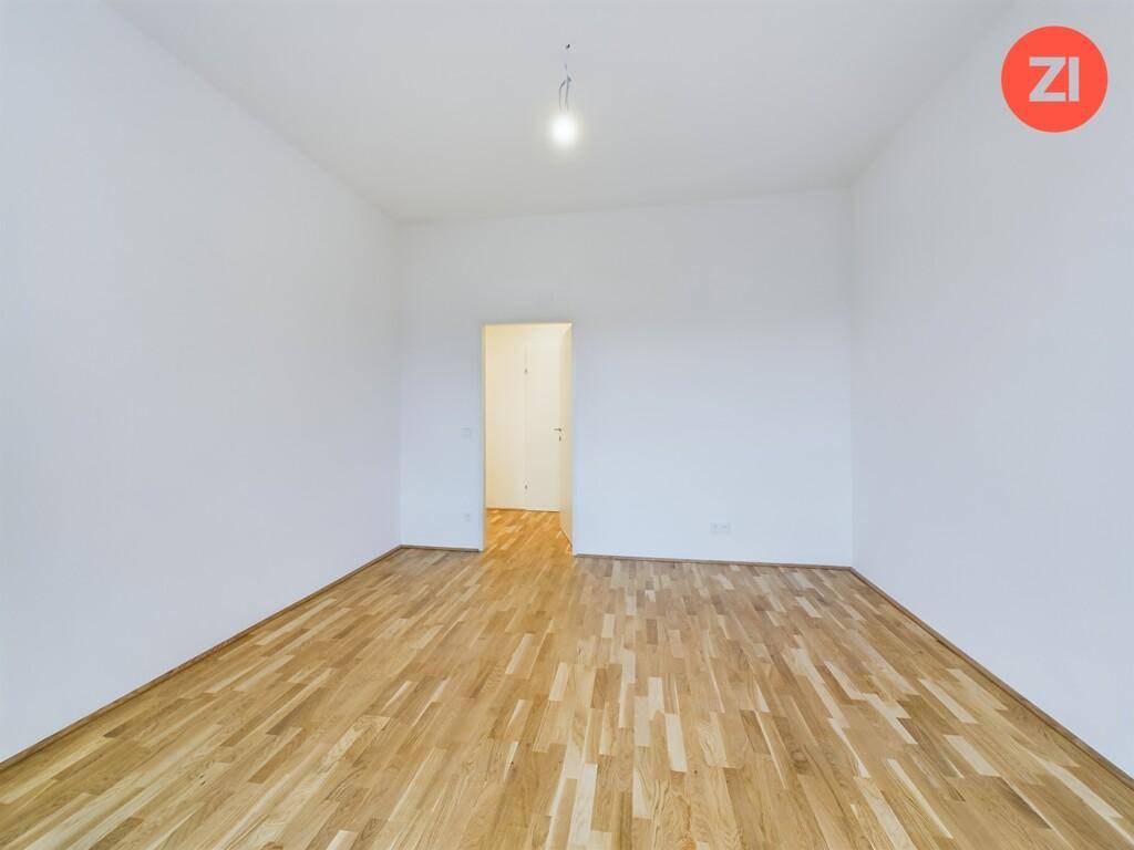 Heller Raum mit Holzboden und weiß gestrichenen Wänden, perfekt als Schlaf- oder Kinderzimmer.
