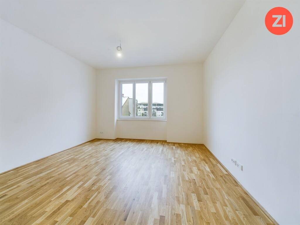 Heller, leerer Raum mit Parkettboden und großen Fenstern, bereit zur individuellen Gestaltung.