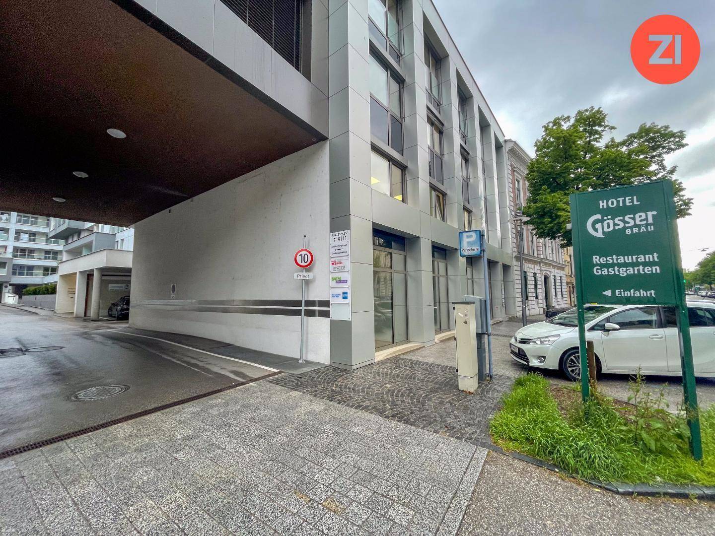 Außenansicht eines modernen Gebäudes mit Hoteleingang und Restaurantbeschilderung an einer städtischen Straße.
