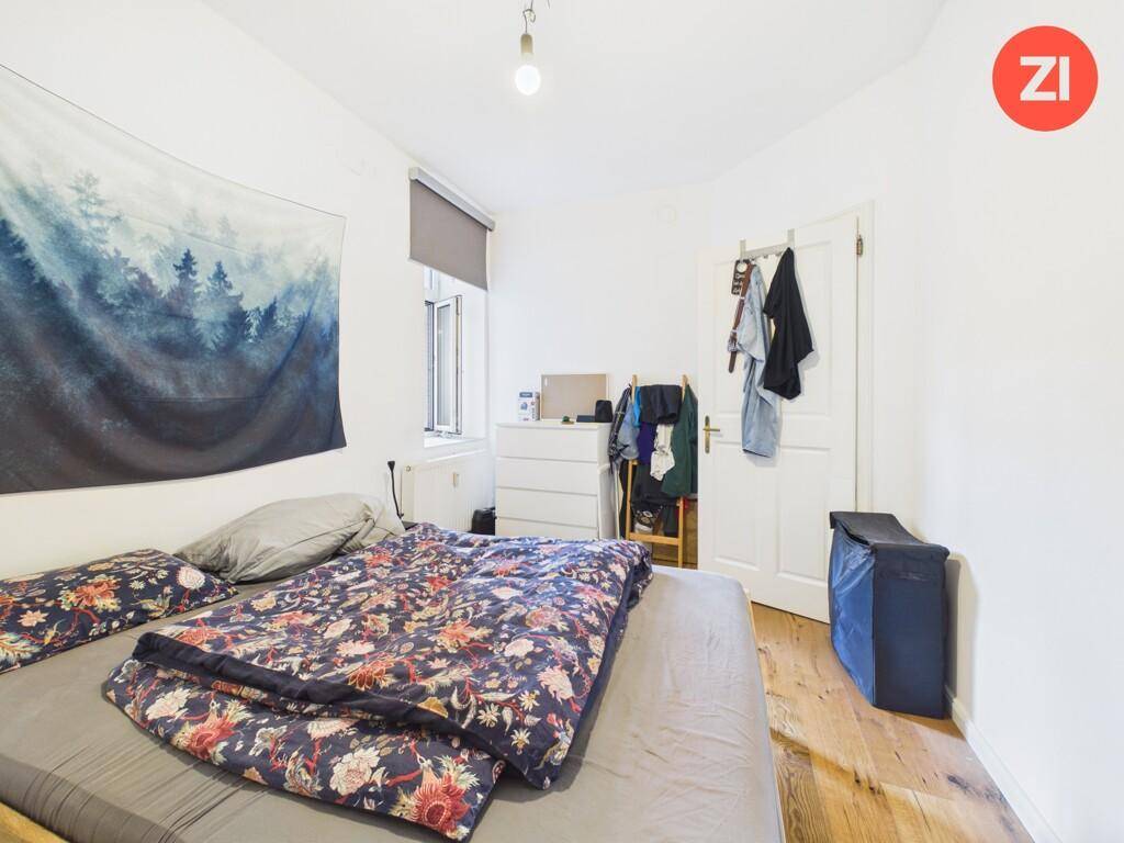 Gemütliches Schlafzimmer mit Holzboden, einem großen Bett und einem Fenster für natürliches Licht.