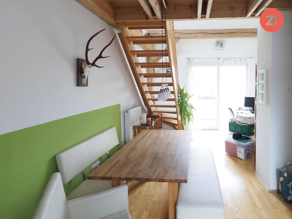 Gemütlicher Essbereich mit Holztisch, Sitzbänken und Hirschgeweih an der Wand.