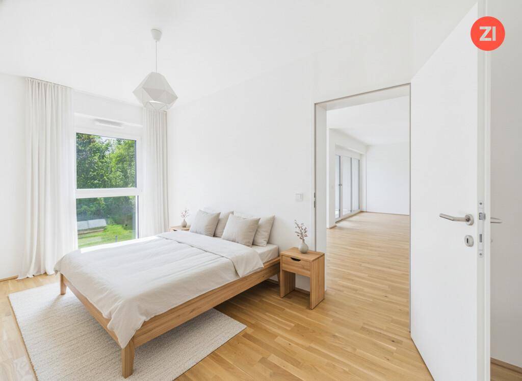 Helles Schlafzimmer mit modernem Holzbett, Parkettboden und großem Fenster mit Blick ins Grüne.