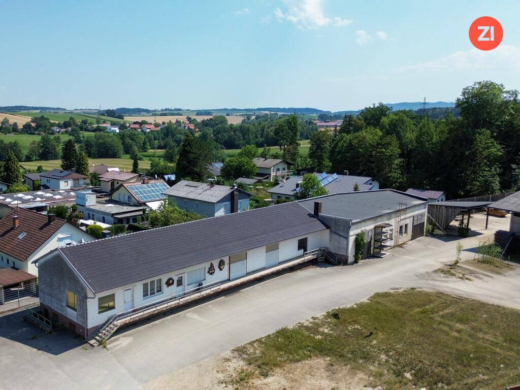 Langes Gebäude mit mehreren Garagentoren und einer Rampe, umgeben von einer großen, unbefestigten Fläche.