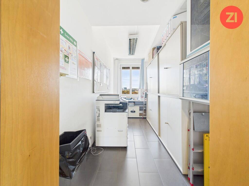 Schmaler Raum mit Fliesenboden, Aktenschränken und einem Fenster am Ende, ideal als Abstellraum.